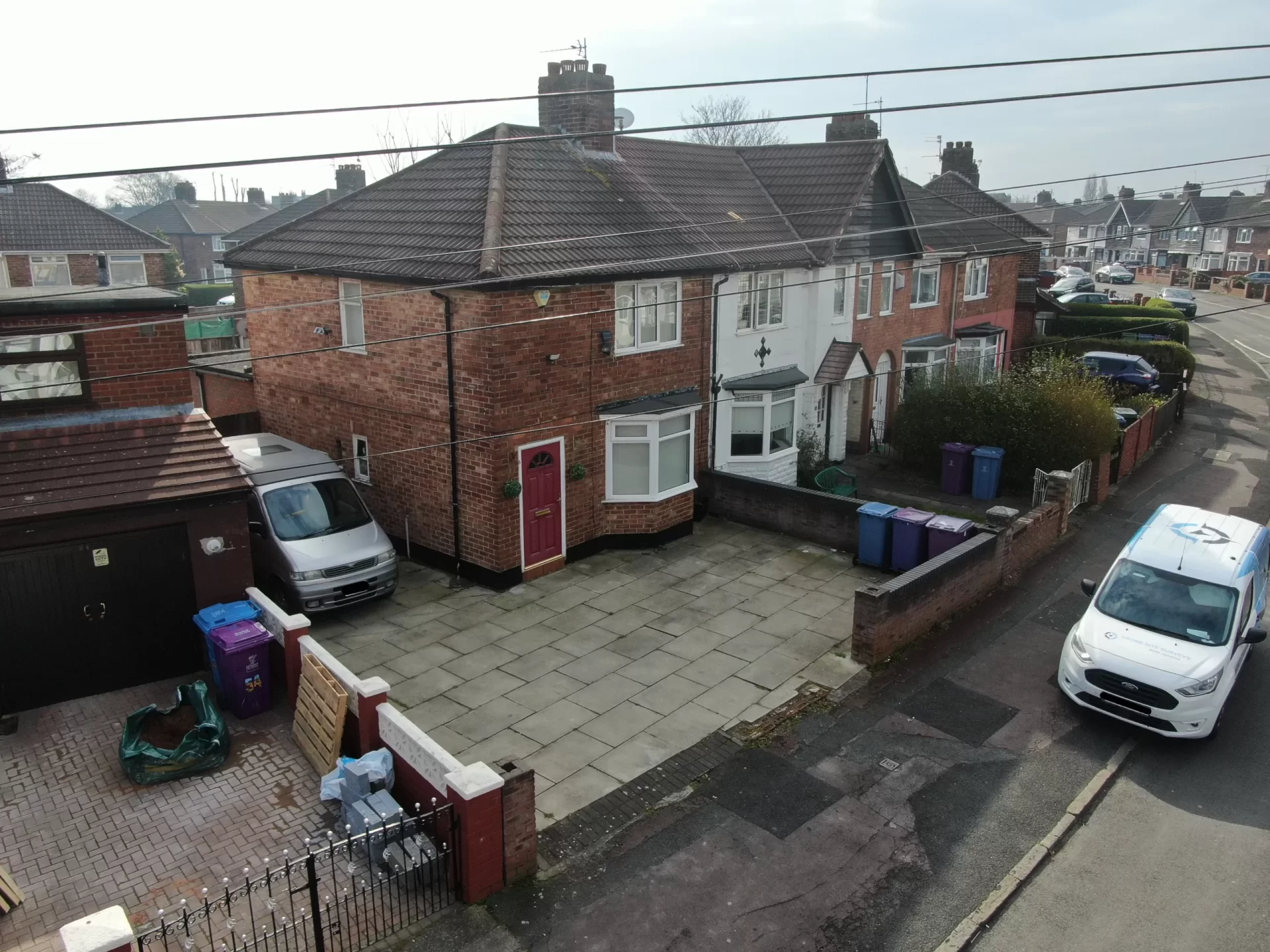 Aerial drone view of an end-terrace house showing the roof, chimney and front elevation